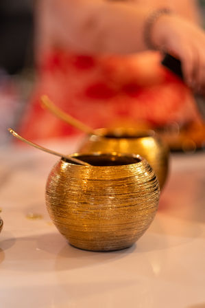 Glittering gold textured condiment bowls with spoons on a restaurant table, warm bokeh background