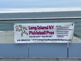 Beachfront banner on Long Island, NY promoting pickleball lessons, clinics, leagues and events with purple lettering and a stick-figure player, ocean and sandy beach in the background.
