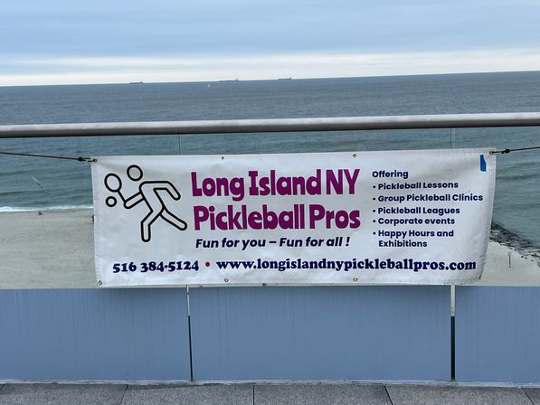 Beachfront banner on Long Island, NY promoting pickleball lessons, clinics, leagues and events with purple lettering and a stick-figure player, ocean and sandy beach in the background.