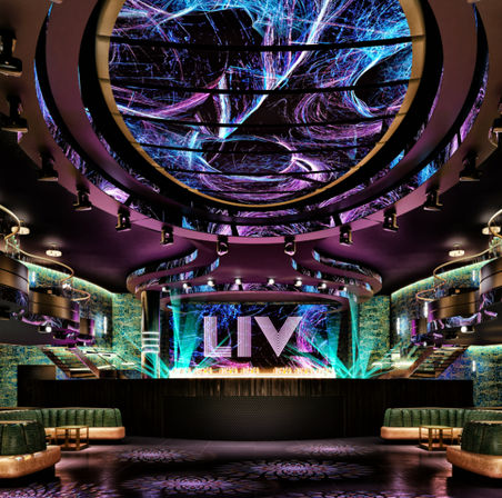 Upscale nightclub interior with swirling neon LED ceiling, illuminated stage with large glowing letters, curved VIP booths and colorful light beams over a dark dance floor.