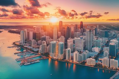 Aerial view of Miami skyline at sunset, waterfront high-rise buildings and marinas reflecting golden light on turquoise Biscayne Bay