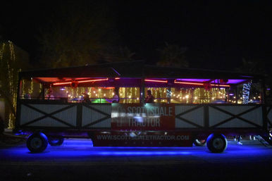 Open-air party trolley with blue underglow, red neon and string lights, silhouetted passengers enjoying a nighttime city street ride.