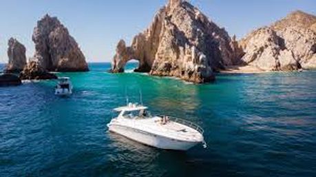 White yacht cruising turquoise waters near the natural rock arch at Land's End, Cabo San Lucas, Mexico