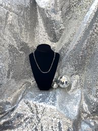 Silver chain necklace on a black velvet bust with two mirrored disco balls on a sparkling silver sequin backdrop — glam jewelry display