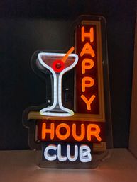 Bright neon martini glass with a red olive and glowing orange "HAPPY HOUR" plus white "CLUB" text on a dark wall — playful bar neon sign for cocktails and nightlife.