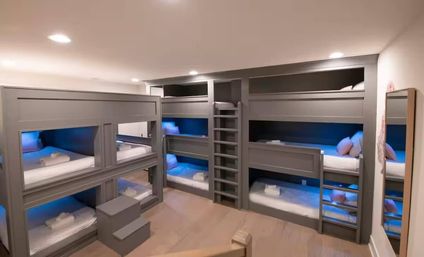 Modern grey built-in bunk beds with stacked sleeping nooks, ladders and blue LED accent lighting in a cozy wood-floored bedroom — family-friendly bunk-room design.
