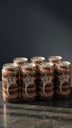 Seven clear cans of layered chocolate dessert (cake and mousse) with crown graphics, arranged on a marble countertop against a dark backdrop.