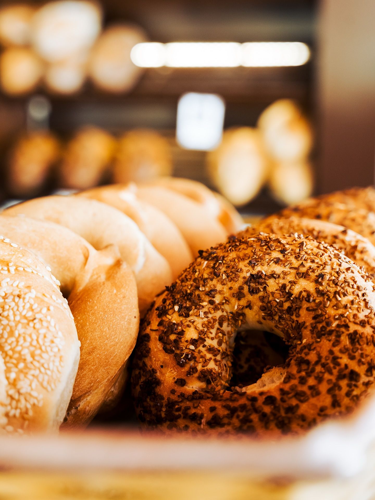Close-up of golden sesame and everything bagels in a bakery display, fresh and crunchy with toasted seeds