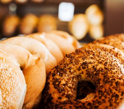 Close-up of golden sesame and everything bagels in a bakery display, fresh and crunchy with toasted seeds