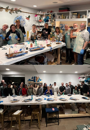 Two stacked photos of cheerful adults in an indoor art studio gathered around a long communal table for a paint/resin workshop, wearing aprons and gloves with trays, brushes, bottles and shelving full of craft supplies in the background.