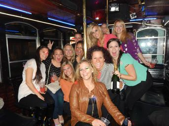 Group of friends laughing on a neon-lit party bus, holding cocktails and a champagne bottle during a lively girls’ night out.