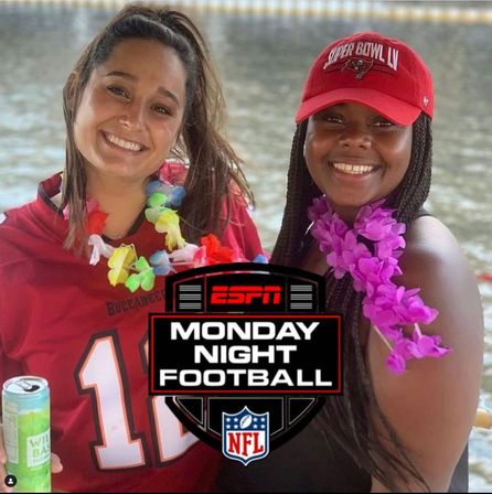 Two smiling women on a waterfront boat wearing Tampa Bay Buccaneers gear and colorful leis, one holding a canned drink, with an ESPN Monday Night Football logo overlaid.