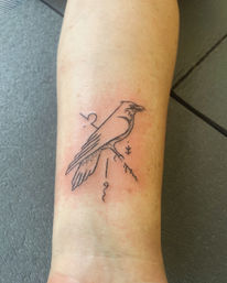 Minimal black-ink line tattoo of a perched crow with geometric accents, subtle dotwork and a tiny branch on the inner forearm