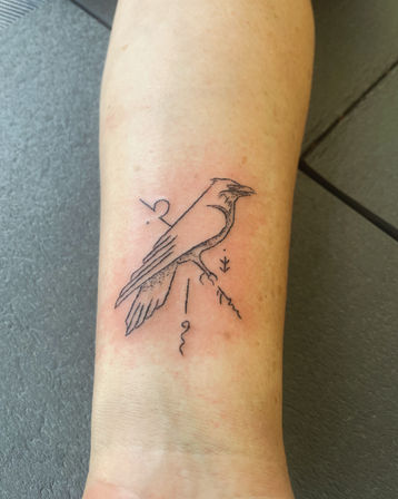 Minimal black-ink line tattoo of a perched crow with geometric accents, subtle dotwork and a tiny branch on the inner forearm