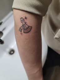 Small black-ink minimalist axe tattoo with a '13' tag and tiny sparkles on the inner forearm