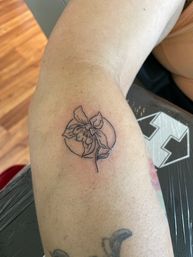 Minimal black linework orchid with crescent moon tattoo on inner forearm, fresh delicate botanical design