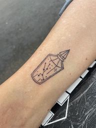 Minimal black-line forearm tattoo of a faceted crystal bottle or vial containing tiny constellation dots and stars, clean dotwork design.