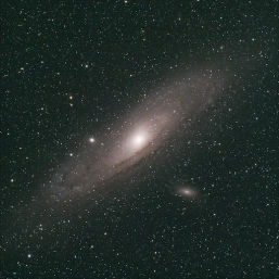 Astrophotography of the Andromeda Galaxy (M31): bright spiral core with sweeping faint arms surrounded by a dense, star-filled night sky