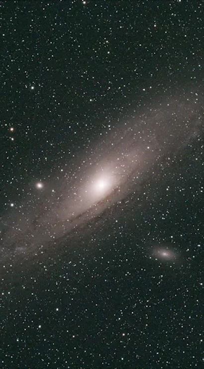 Astrophotography of the Andromeda Galaxy (M31): bright spiral core with sweeping faint arms surrounded by a dense, star-filled night sky