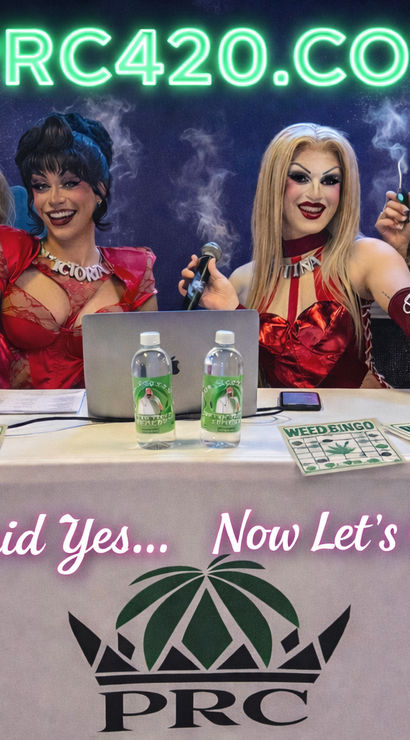 Bachelorette party with bridesmaids in veils and two drag hosts at a cannabis-themed table with weed-bingo cards, vaping props, neon sign and banner reading "She Said Yes... Now Let's Get Lit."