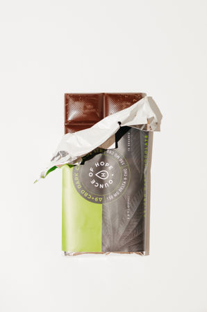 Partially unwrapped dark chocolate bar showing four squares, green-and-gray paper and silver foil wrapper on a clean white background