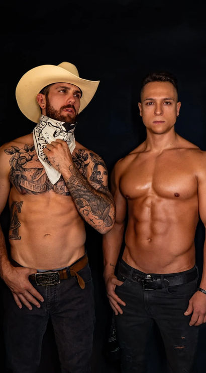 Four shirtless male models in a cowboy-themed fitness photoshoot, wearing jeans, cowboy hats and bandanas, showcasing tattoos and sculpted abs against a black backdrop.