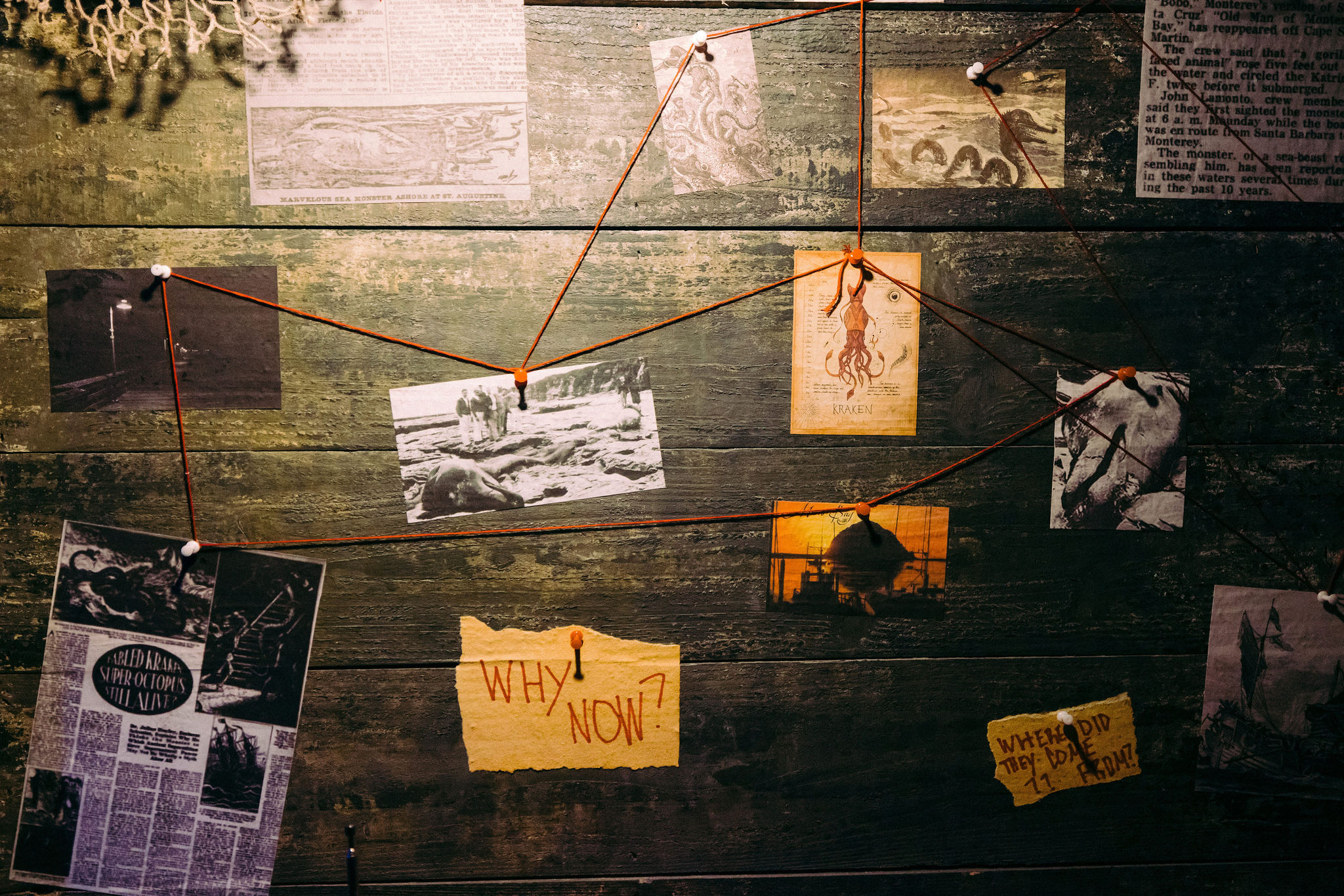 Conspiracy-style investigation board on weathered wood with vintage maritime clippings, kraken illustration, black-and-white photos, red string connections and a yellow note reading "WHY NOW?"