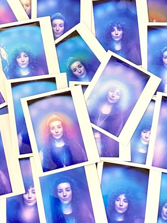 Stack of Polaroid-style portrait photos showing a woman bathed in dreamy blue, purple and pink aura halos, overlapping to create an ethereal studio portrait collage.