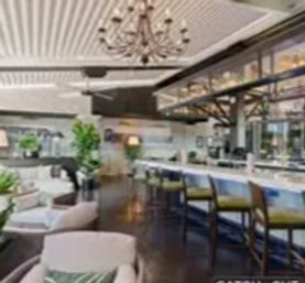 Upscale modern restaurant and bar interior with marble countertop, green bar stools, chandeliers, cozy lounge seating and indoor plants