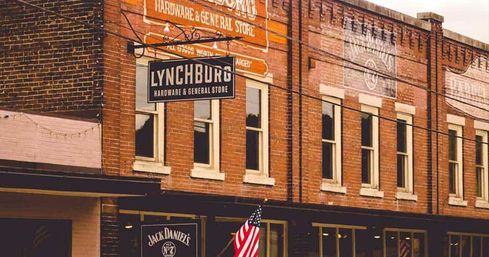 Small-town main street with red-brick storefronts, a vintage hardware and general store sign, an American flag on the sidewalk, and warm nostalgic tones.
