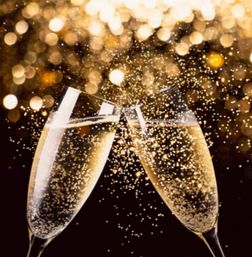 Two champagne flutes clinking, golden bubbles fizzing against warm bokeh lights — festive celebration toast.