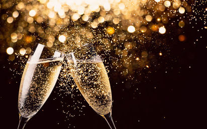 Two champagne flutes clinking with golden bubbles and sparkling bokeh background, festive celebration scene.