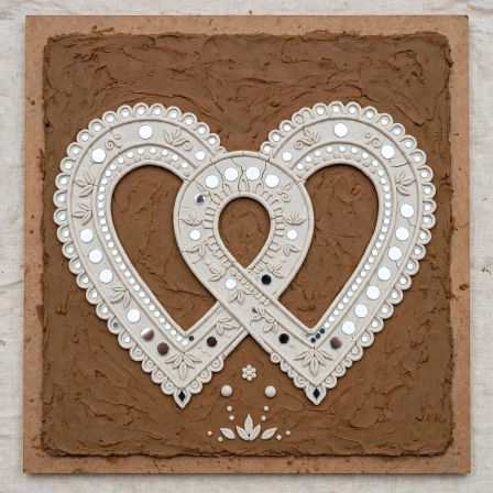 Interlocking white ceramic heart mosaic with small mirrored dots and floral carvings mounted on a textured brown clay panel — handmade boho wall art, rustic neutral home décor