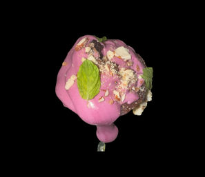 Bright pink-glazed dessert pop on a stick with chocolate base, crushed nuts and fresh mint leaves, isolated on black background