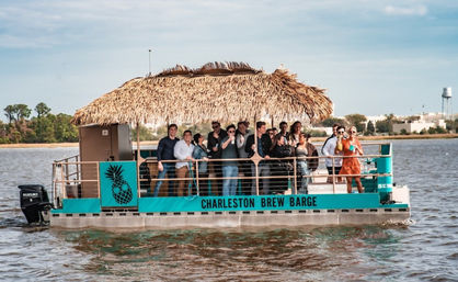 Group of people enjoying drinks on a turquoise, thatched-roof party barge cruising Charleston harbor