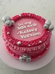 Pink birthday cake with ruffled buttercream, white piped message referencing being in your 30s, glittered top, silver dragees and small disco-ball cake toppers