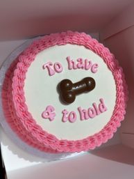 Round white cake with pink ruffled buttercream border, pink letters reading 'To have & to hold' and a chocolate bone-shaped topper — playful wedding/bridal shower cake.