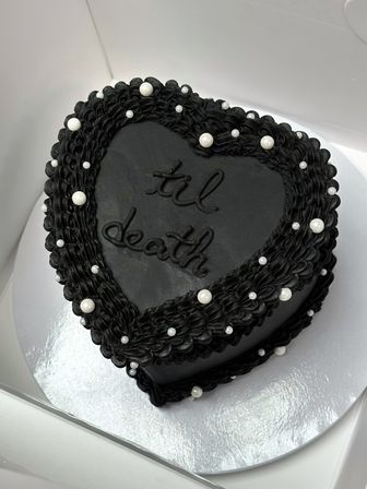 Heart-shaped black buttercream cake with ruffled border, scattered white edible pearls and "til death" piping — gothic-style wedding or Halloween dessert.