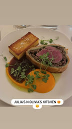 Medium-rare beef Wellington slice in flaky pastry, plated with a golden seared polenta cake, bright carrot purée, rich brown jus and fresh pea microgreens — elegant gourmet entrée.