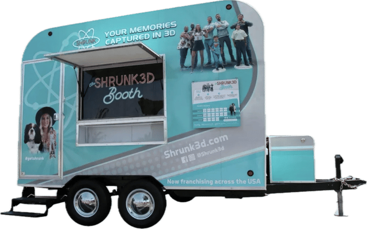 Teal mobile 3D photo booth trailer with service window, dual-axle wheels, hitch and family graphics for events