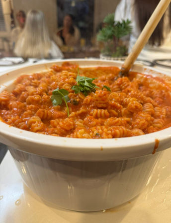 Close-up of steaming rotini pasta in rich tomato sauce, garnished with parsley in a white baking dish on a cozy dinner table