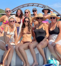 Group of friends on a boat under an arched bridge, smiling in swimsuits, sunglasses and sun hats on a sunny summer river cruise.
