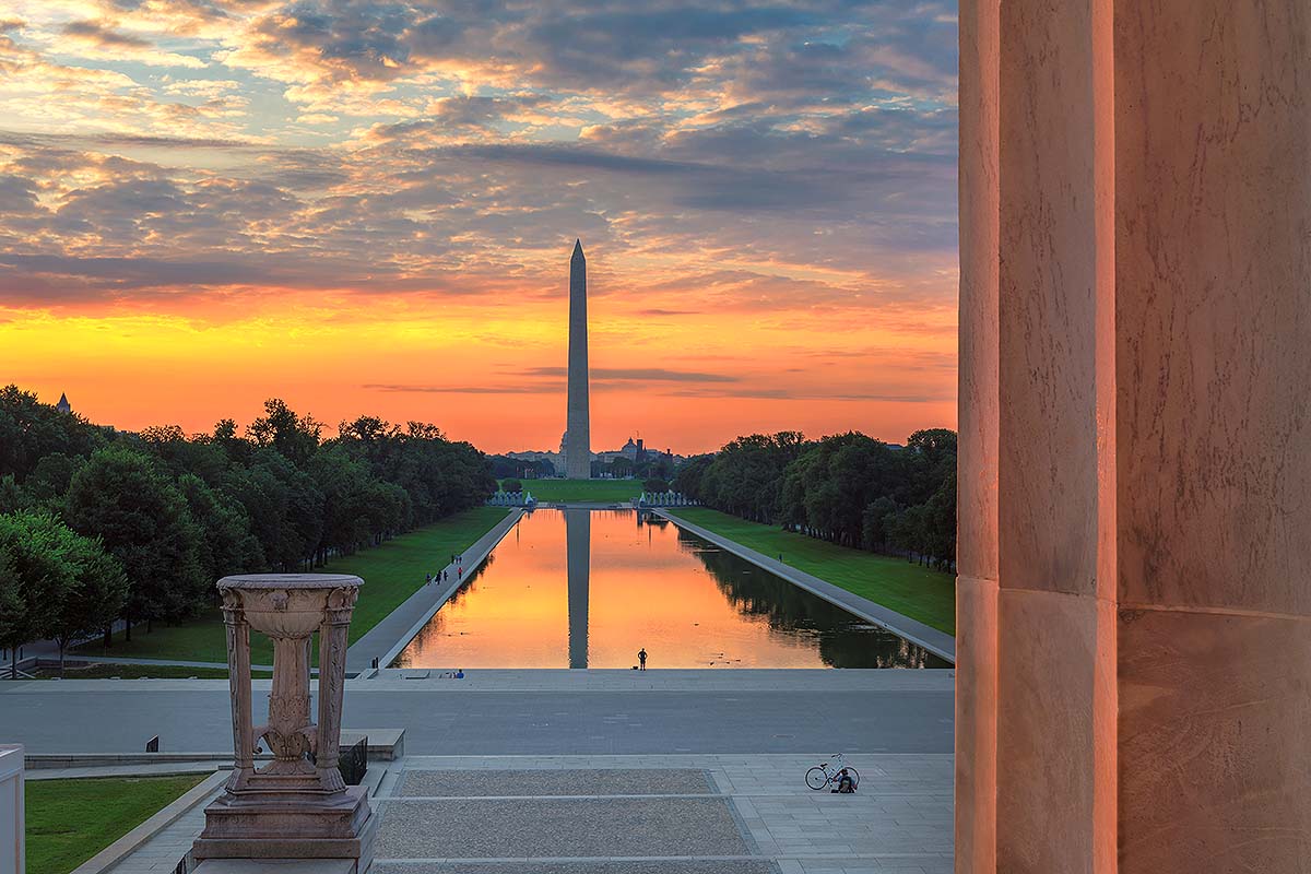 Golden sunrise over the Washington Monument reflected in the Lincoln Memorial Reflecting Pool with tree-lined National Mall in Washington, D.C.