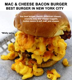 Overstuffed mac-and-cheese bacon burger with gooey cheddar macaroni spilling from a toasted brioche bun, bacon and beef patty peeking through, drizzled with mildly spicy orange sauce on parchment — promotional shot touting a New York City favorite.