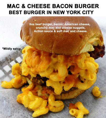 Overstuffed mac-and-cheese bacon burger with gooey cheddar macaroni spilling from a toasted brioche bun, bacon and beef patty peeking through, drizzled with mildly spicy orange sauce on parchment — promotional shot touting a New York City favorite.