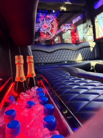 Luxury party limo interior with quilted leather seats, red LED lighting, ice bin holding champagne bottles and blue-capped water, Valentine's Day window decor