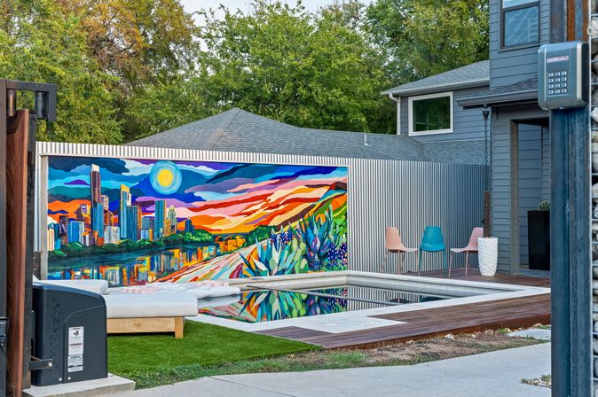 Modern backyard with a rectangular pool reflecting a vibrant city skyline mural and colorful sunset sky, lounge cushions, pastel chairs and wooden deck
