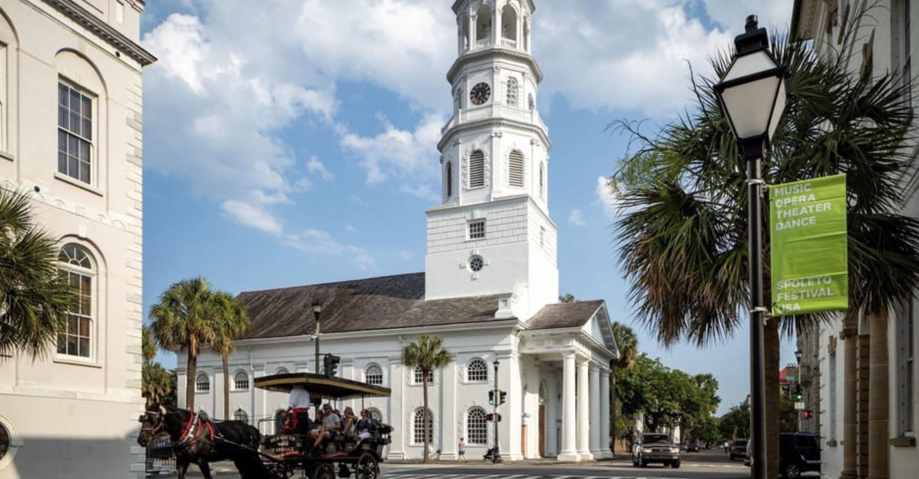 Historic white steepled church on a sunny Southern downtown street, horse-drawn carriage passing palm trees under a blue sky.