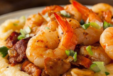 Close-up of Southern-style shrimp and grits: grilled shrimp and crispy bacon on creamy cheese grits, garnished with chopped green onions.