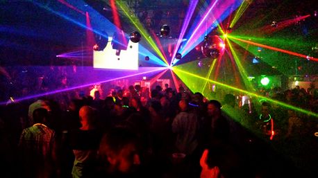 Crowded nightclub dance floor with multicolored laser beams, mirrored disco balls and people dancing in a lively urban nightlife scene.
